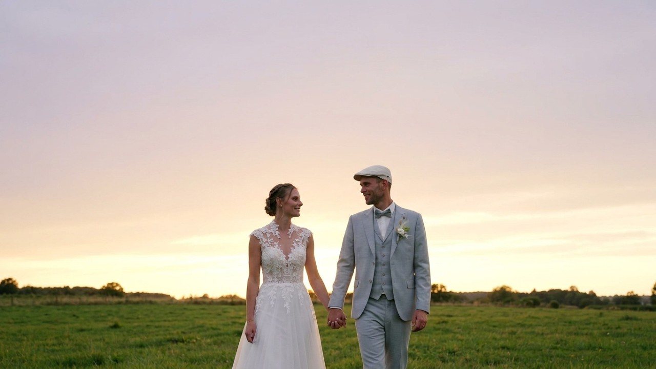 Les mariés marchent main dans la main au coucher du soleil, image du film de leur mariage